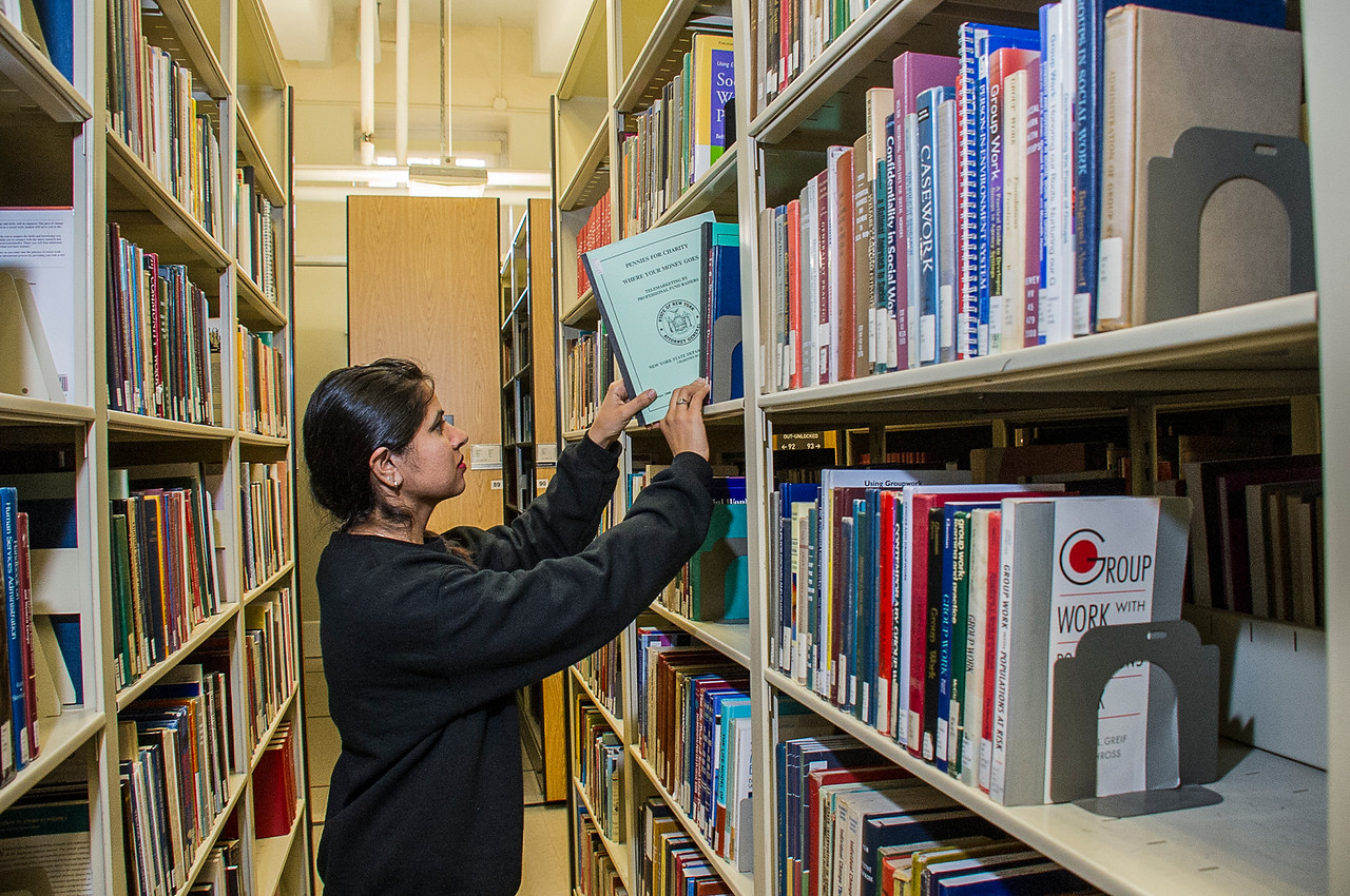 Retrieving books from shelves at Dewey Library on the Downtown Campus. Photos: Mark Schmidt