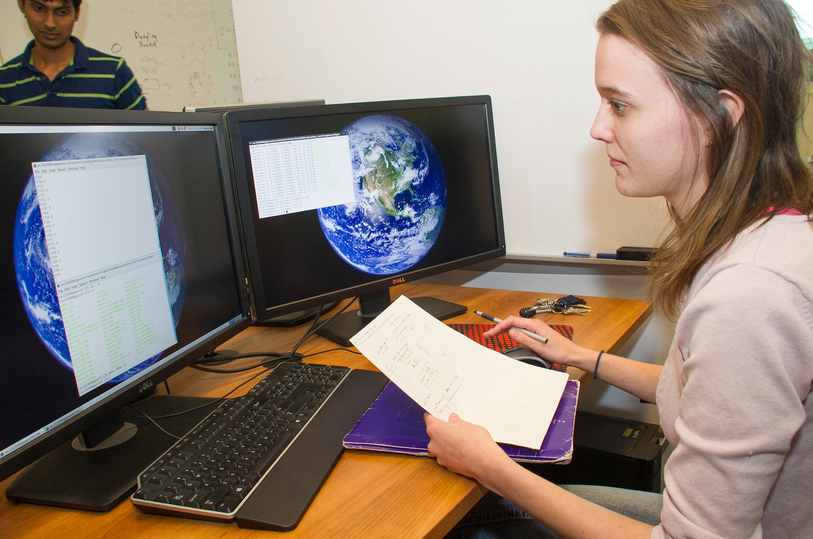 Student intern at computer with code and papers