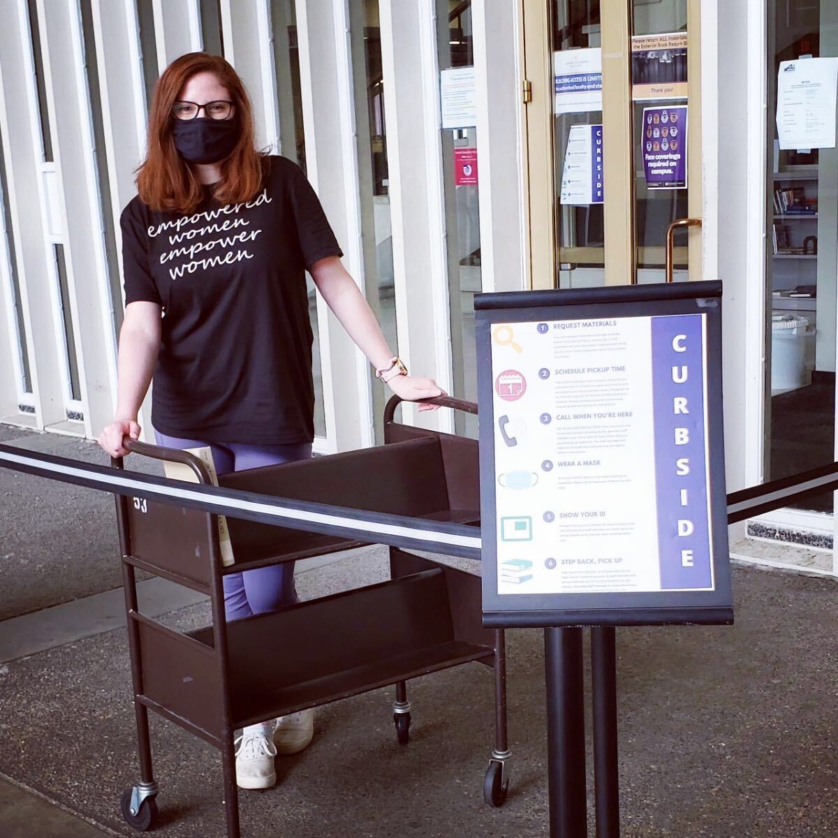 A staff member brings books out to the curbside pickup location