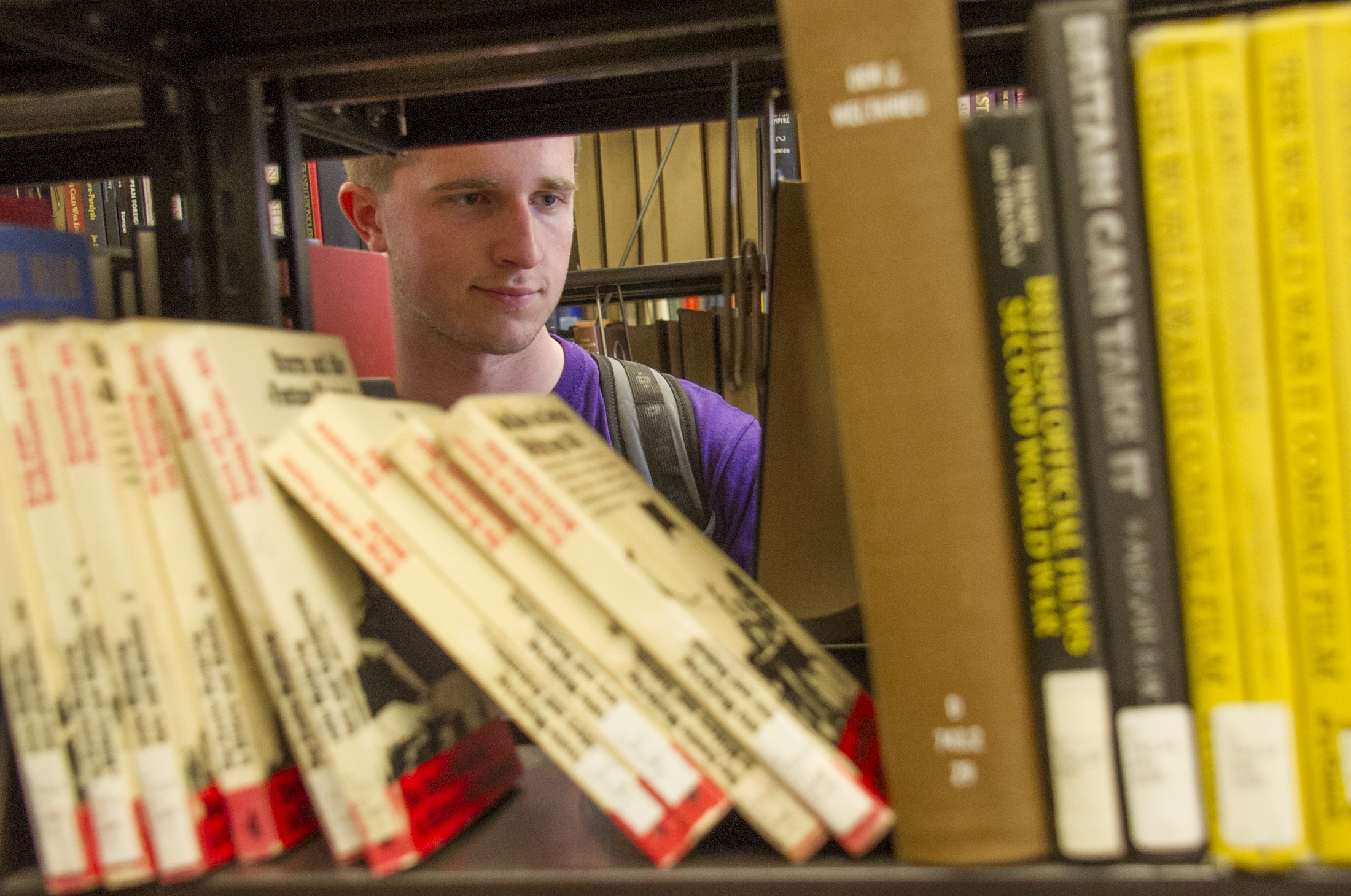 student looking for books on library shelves