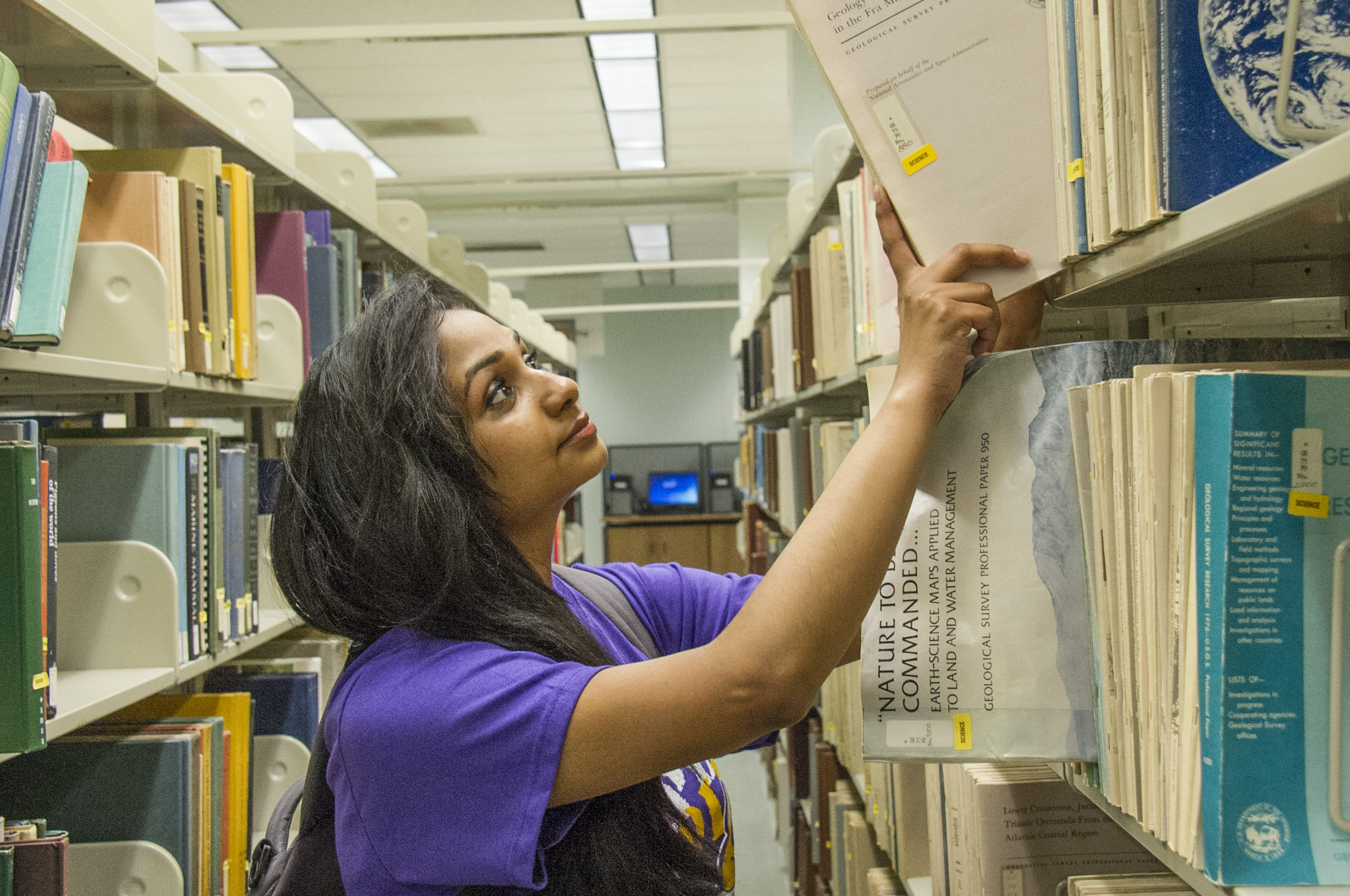 student pulling book from science library