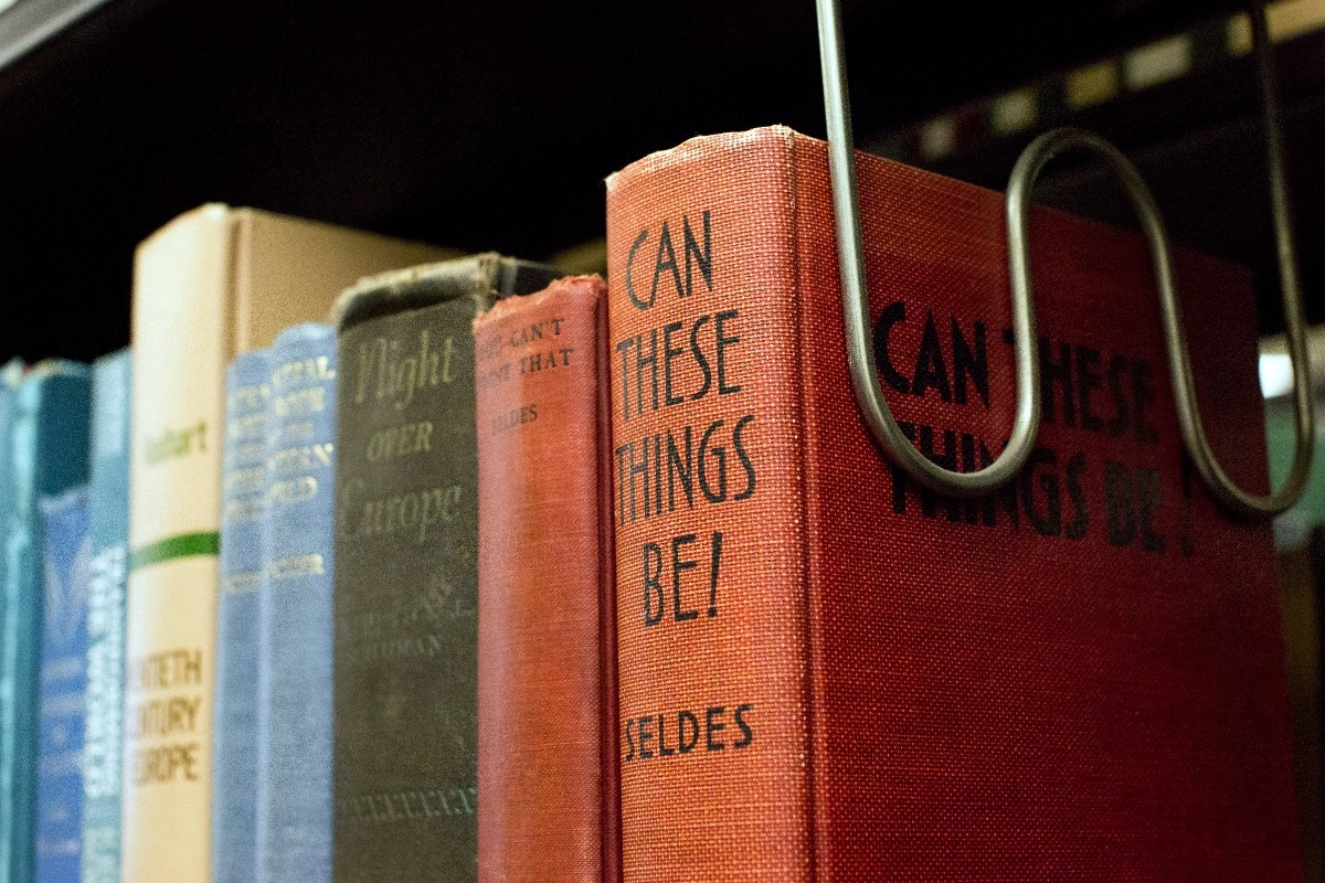 A row of library books on a shelf in the library. You can see their spines, one reads "Can These Things Be?"