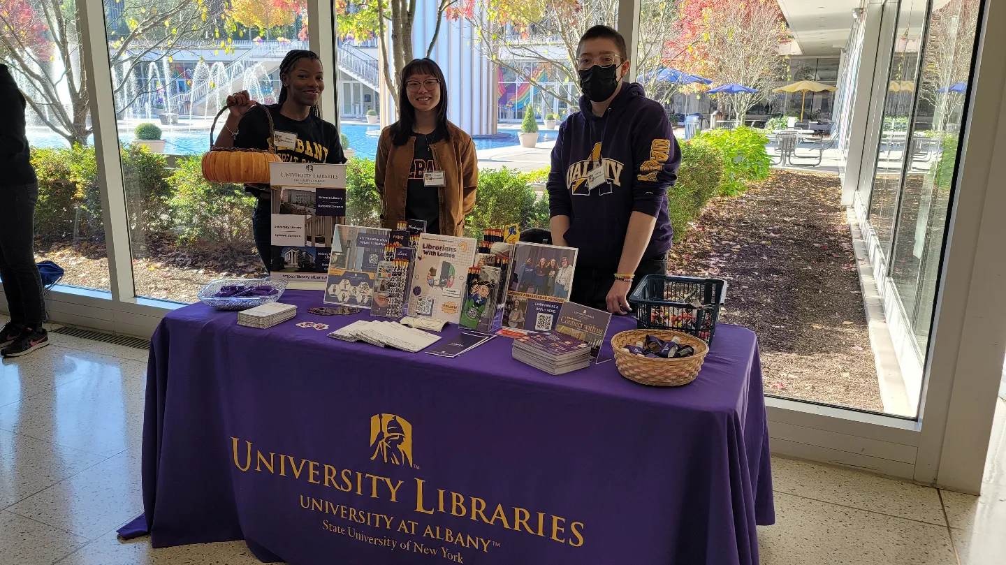 Three ambassadors with a table filled with marketing materials for the University Libraries