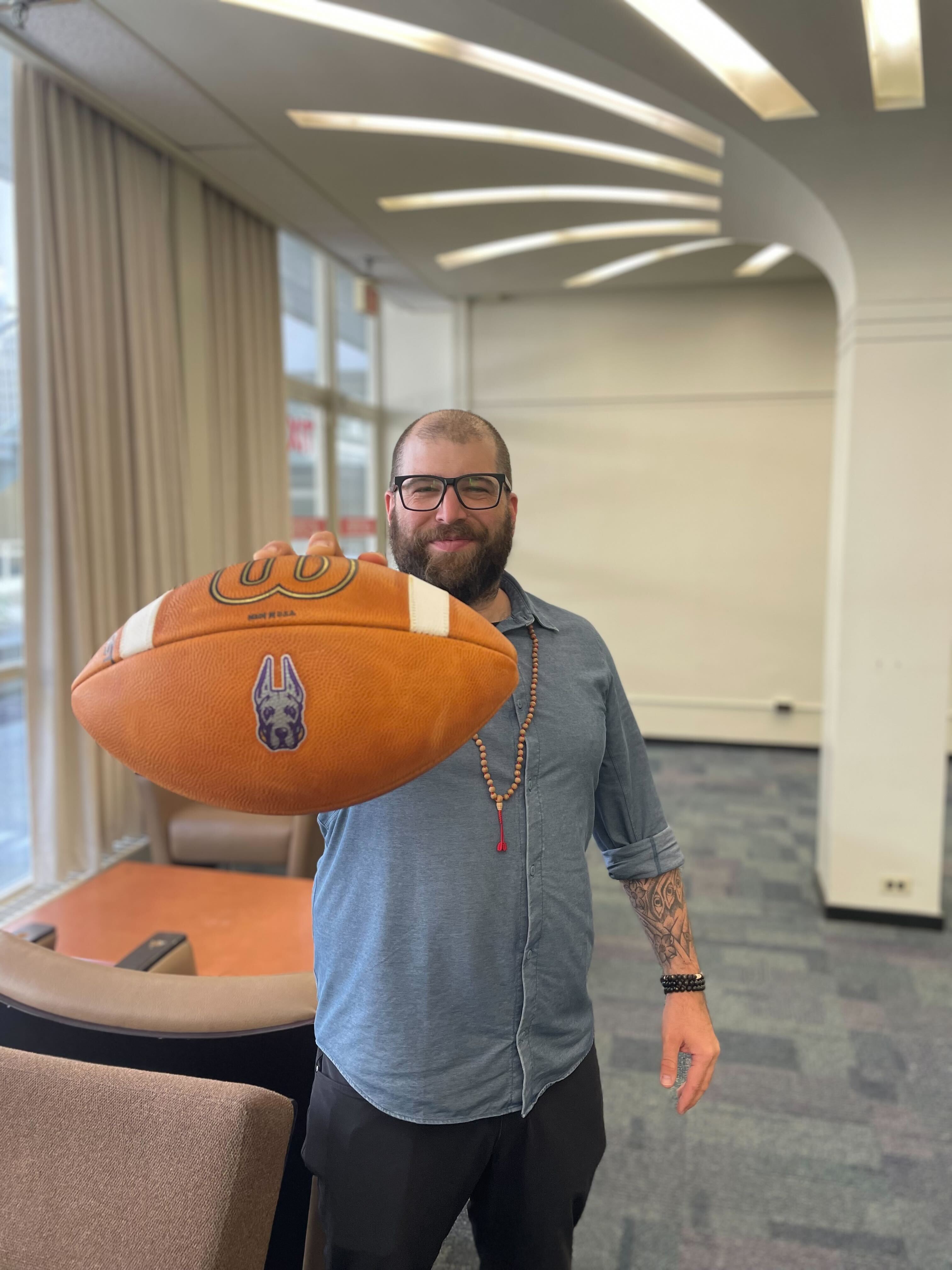 Ryan Clow posing with a UAlbany football