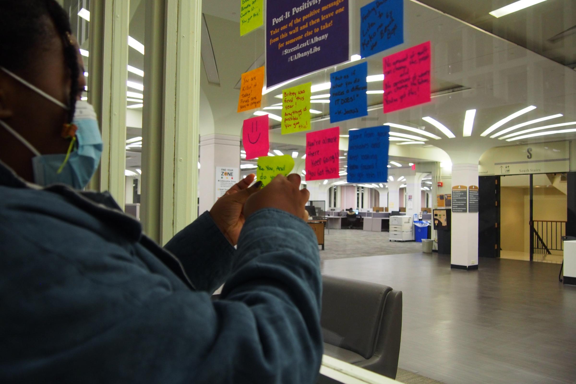 Student adds to the Post-it Positivity Wall