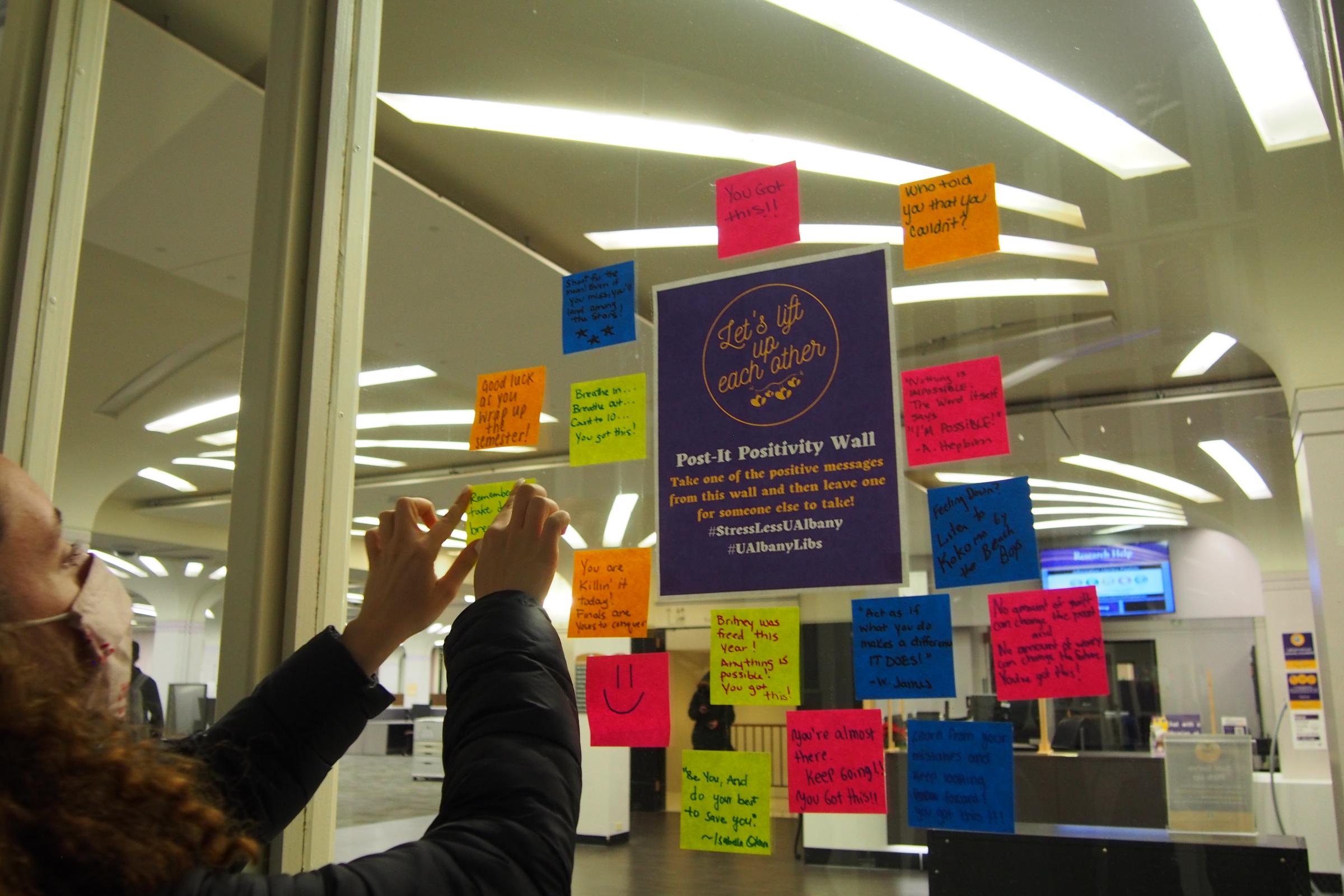 Student adds to the Post-it Positivity Wall