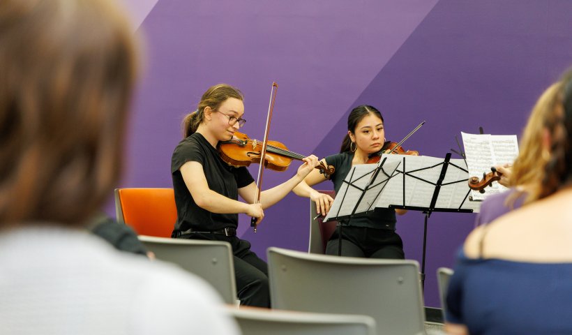 Two students playing violins during a Live at the Library concert. 
