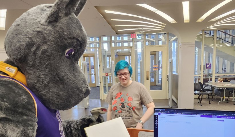Damien the Great Dane checking out a book to a student