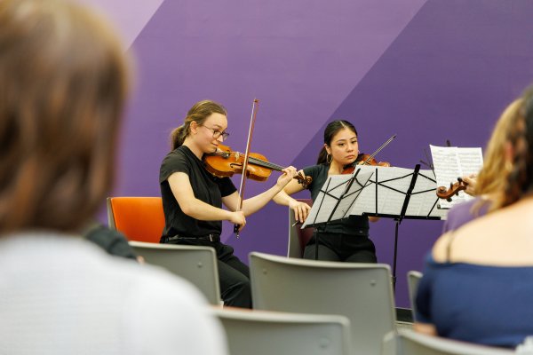 Two students playing violins during a Live at the Library concert. 