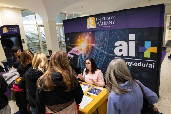Students gathering around the AI Plus table at Showcase