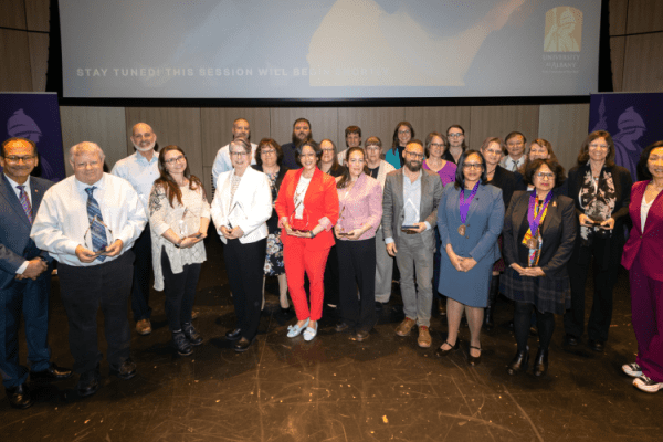 Lauren Puzier poses with President Rodriguez, Provost Kim, and other award winners in the Campus Center Auditorium.