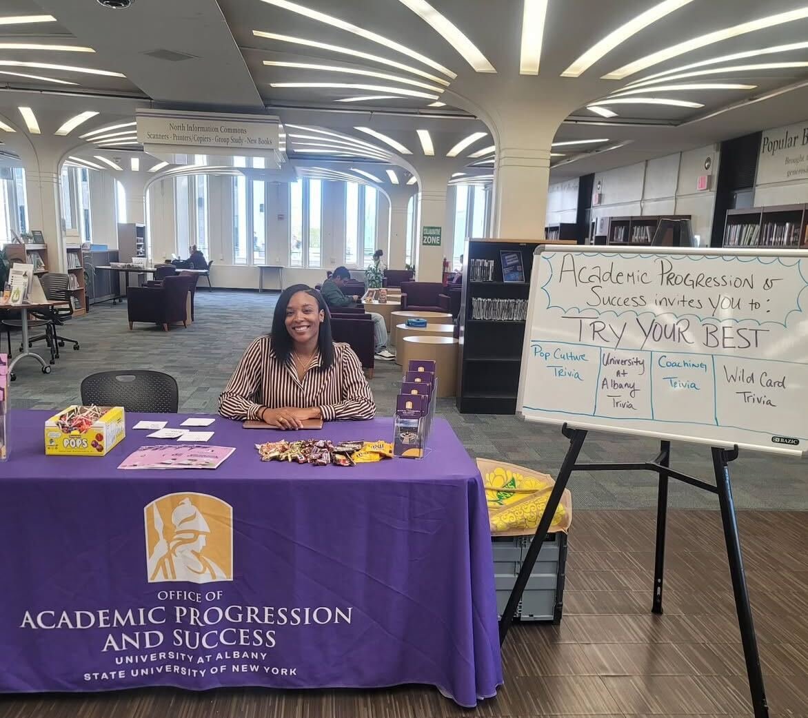 A woman in a purple sweater tabling in the library