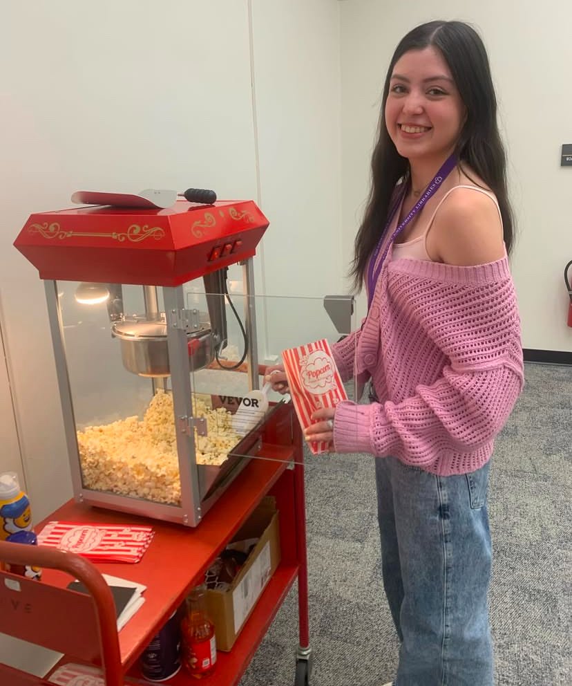 A woman student in a pink sweater preparing a bag of popcorn