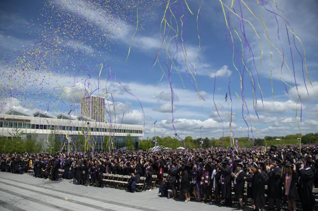 Purple and gold streamers raining down on graduates assembled at the Entry Plaza