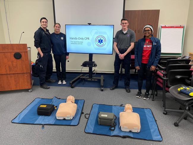 Volunteers from Five Quad Ambulance Service posing behind CPR dummies
